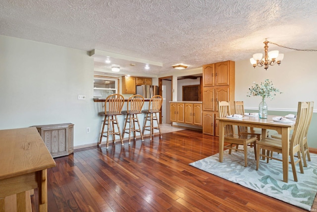 dining area featuring a notable chandelier, dark wood-type flooring, and a textured ceiling