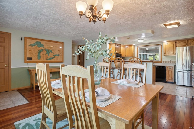 dining area with a textured ceiling, wood-type flooring, and a chandelier