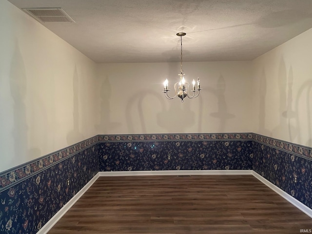 unfurnished dining area featuring wallpapered walls, visible vents, a chandelier, and wainscoting