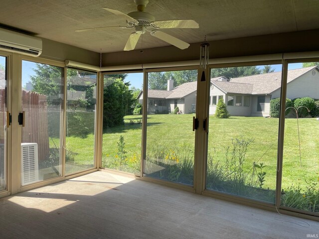 unfurnished sunroom featuring a wall mounted AC and ceiling fan