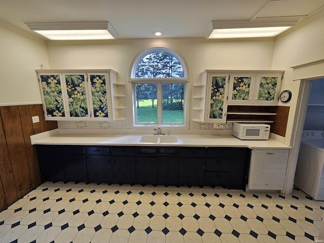 kitchen with washer / clothes dryer, wooden walls, sink, and white appliances