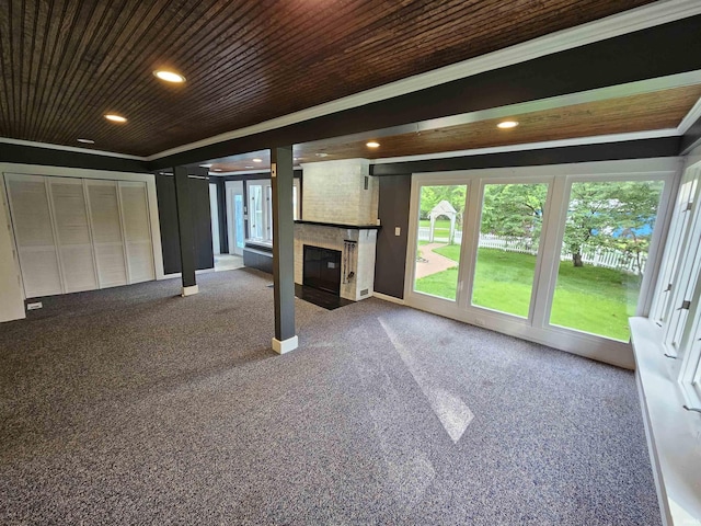 unfurnished living room with carpet flooring, ornamental molding, a large fireplace, and wooden ceiling