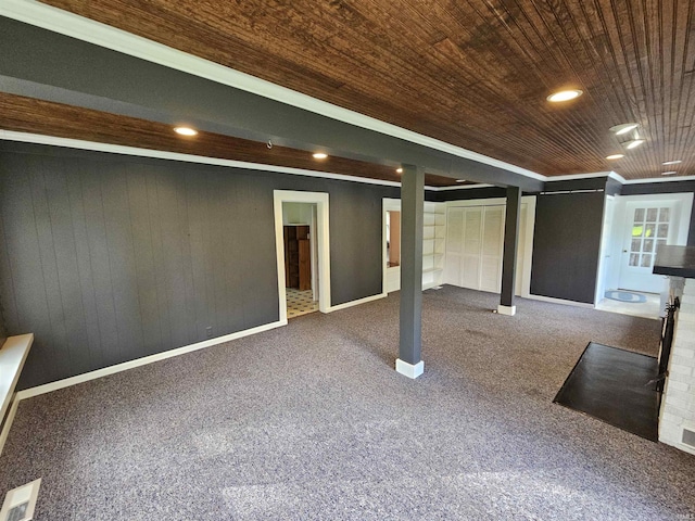 basement with wooden walls, crown molding, carpet, and wood ceiling