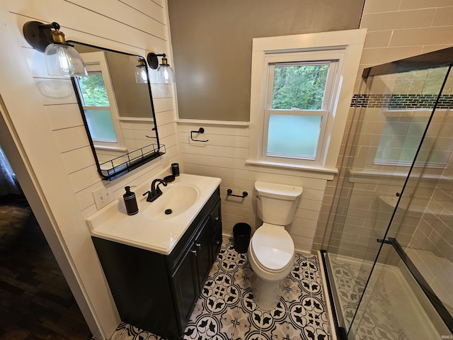 bathroom featuring tile patterned flooring, vanity, toilet, and a shower with door