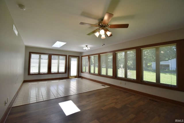 unfurnished room featuring ceiling fan, dark hardwood / wood-style flooring, and a skylight