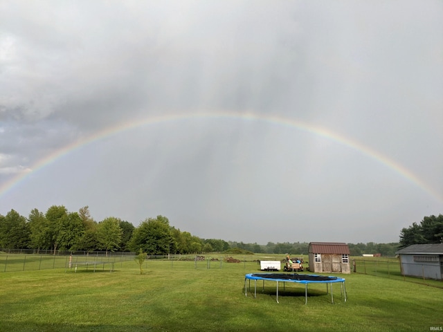 view of yard featuring a storage shed, a rural view, and a trampoline