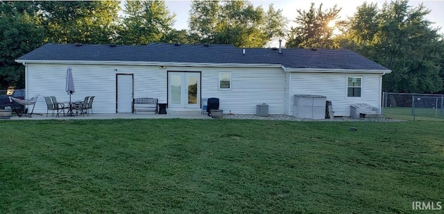 back house at dusk with central air condition unit, a yard, and a patio area