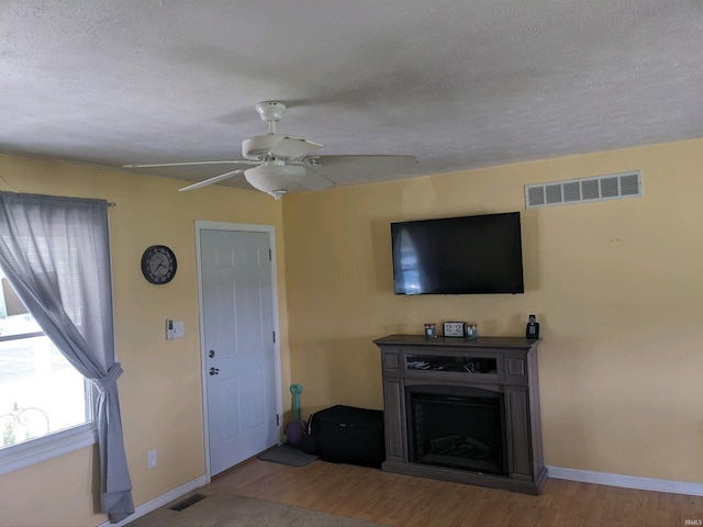 unfurnished living room with a textured ceiling, light hardwood / wood-style flooring, and ceiling fan