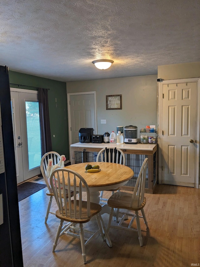 dining area with a textured ceiling and light hardwood / wood-style flooring