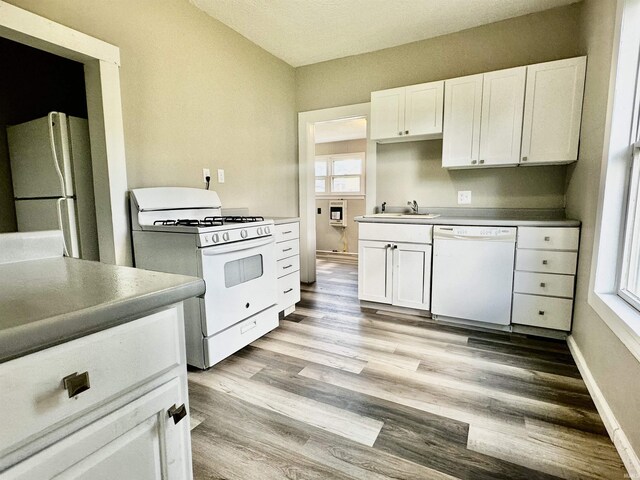 kitchen with white appliances, light hardwood / wood-style floors, white cabinetry, and a wealth of natural light