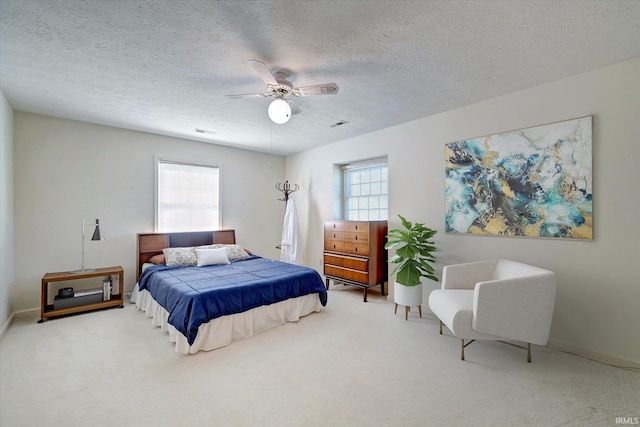 carpeted bedroom featuring baseboards, a textured ceiling, visible vents, and a ceiling fan