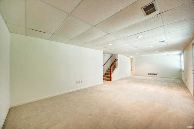 below grade area with light carpet, stairway, baseboards, and visible vents