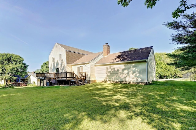 back of property with a deck, a lawn, and a chimney