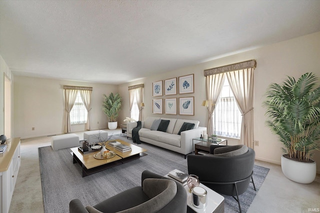 living area with light carpet, a textured ceiling, and baseboards