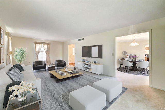 carpeted living area with visible vents and a notable chandelier