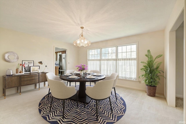 dining area featuring an inviting chandelier, baseboards, a textured ceiling, and light colored carpet