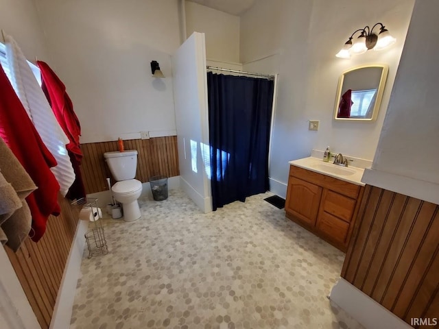 bathroom featuring plenty of natural light, toilet, wooden walls, vanity, and a shower with shower curtain