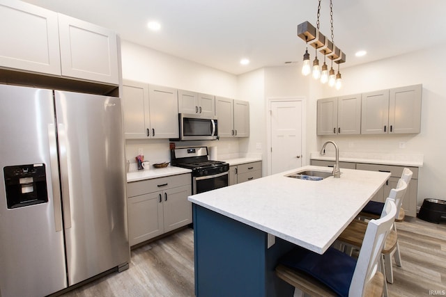 kitchen featuring gray cabinetry, sink, light hardwood / wood-style flooring, a kitchen island with sink, and appliances with stainless steel finishes