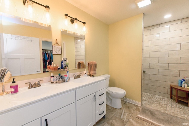 bathroom with vanity, toilet, and a tile shower