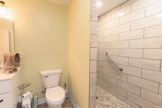 bathroom with tiled shower, vanity, and toilet