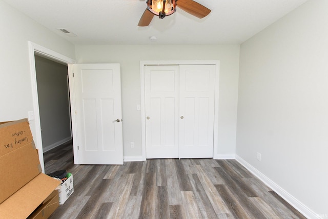 unfurnished bedroom with ceiling fan, dark wood-type flooring, and a closet