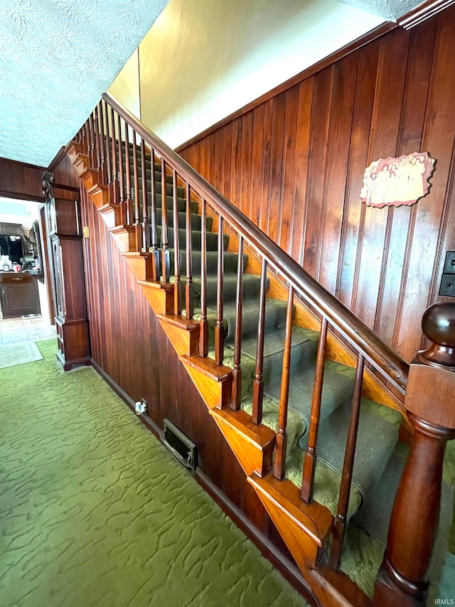 staircase with carpet flooring and wooden walls