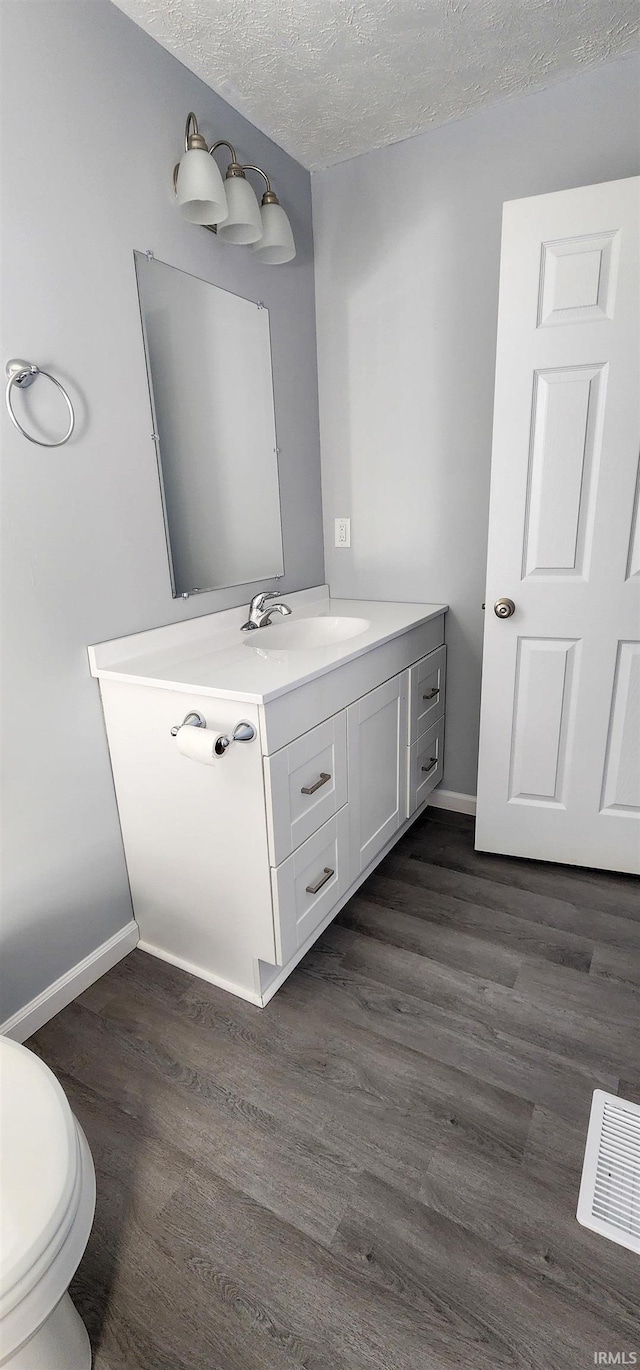 bathroom with vanity, hardwood / wood-style floors, toilet, and a textured ceiling