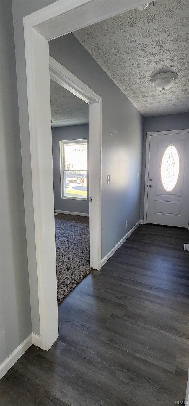 entryway with dark wood-type flooring and a textured ceiling