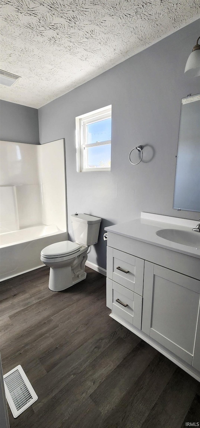 full bathroom with toilet, wood-type flooring, a textured ceiling, shower / bathtub combination, and vanity