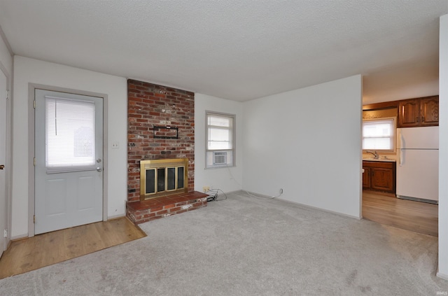 unfurnished living room with a fireplace, light colored carpet, a textured ceiling, and sink