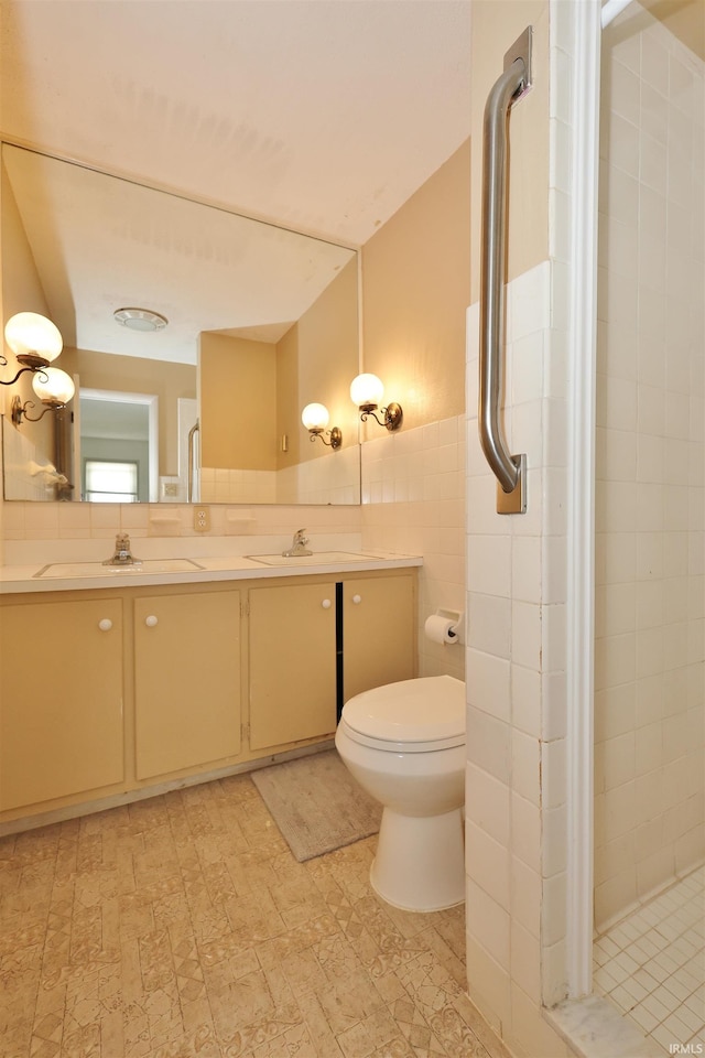 bathroom featuring vanity, a shower with door, toilet, and tile walls