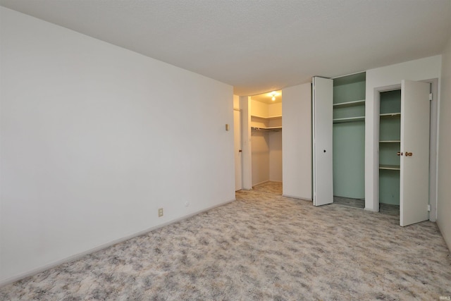 unfurnished bedroom with a walk in closet and light colored carpet