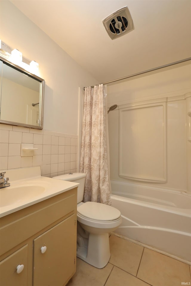 full bathroom featuring shower / bathtub combination with curtain, tile patterned floors, toilet, vanity, and tile walls