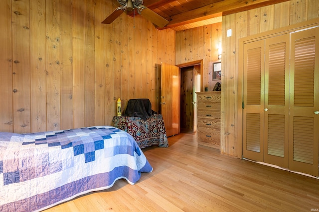 bedroom featuring wood walls, wooden ceiling, hardwood / wood-style flooring, ceiling fan, and beamed ceiling