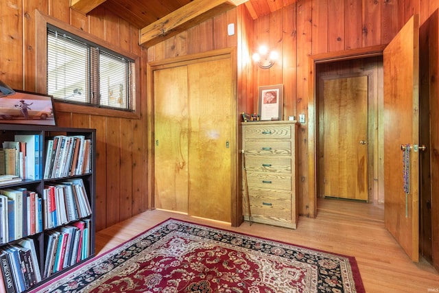 interior space featuring wood walls, wooden ceiling, beam ceiling, and light hardwood / wood-style flooring