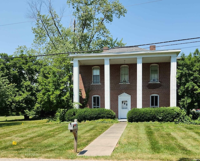 neoclassical / greek revival house featuring a front lawn and brick siding