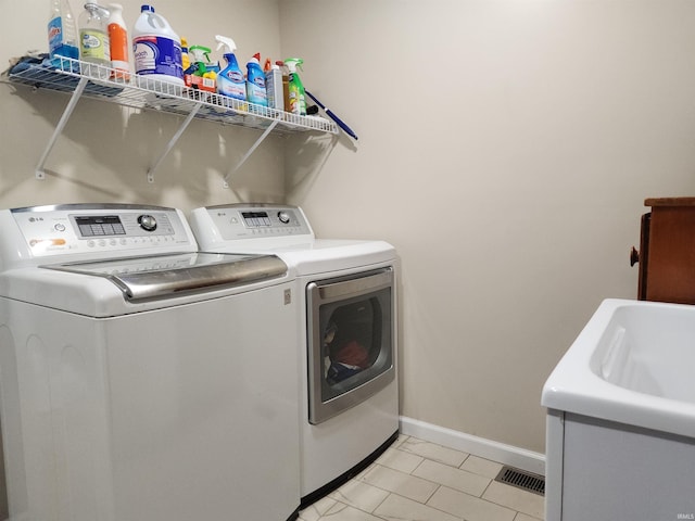 washroom with laundry area, visible vents, baseboards, and washing machine and clothes dryer