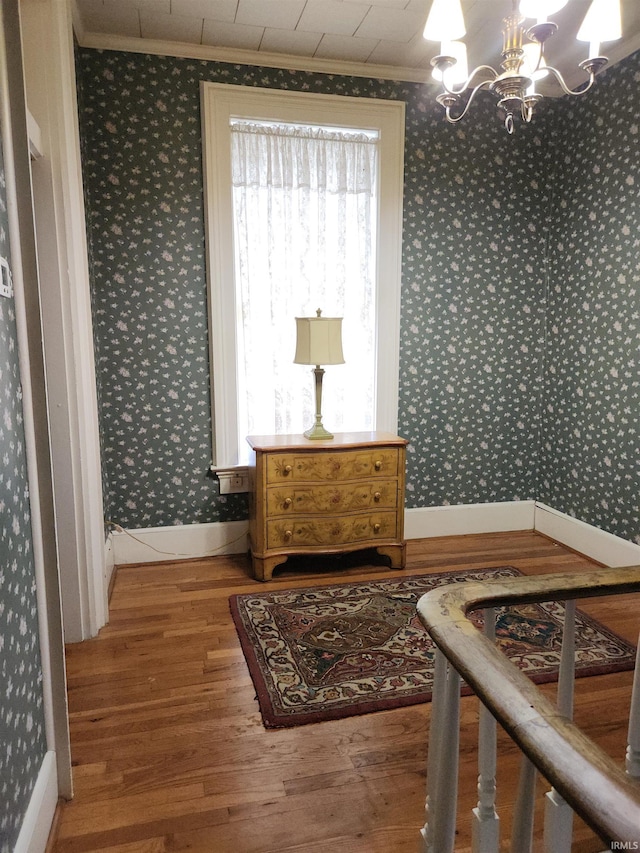 interior space featuring ornamental molding, wood finished floors, and wallpapered walls