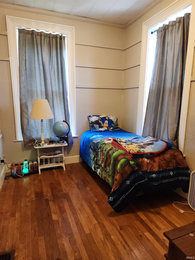 bedroom with visible vents, ornamental molding, and wood finished floors