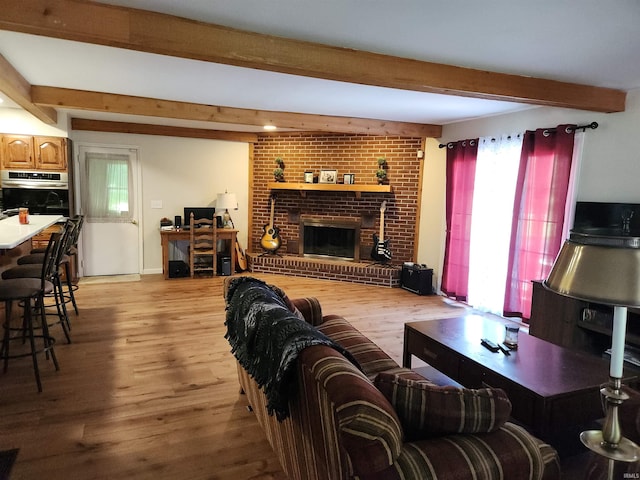 living room featuring a fireplace, beamed ceiling, and light wood finished floors