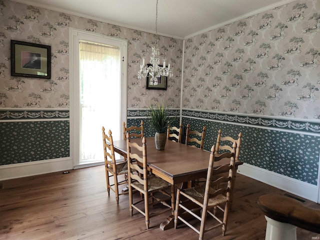 dining room featuring wood finished floors, baseboards, wainscoting, wallpapered walls, and crown molding