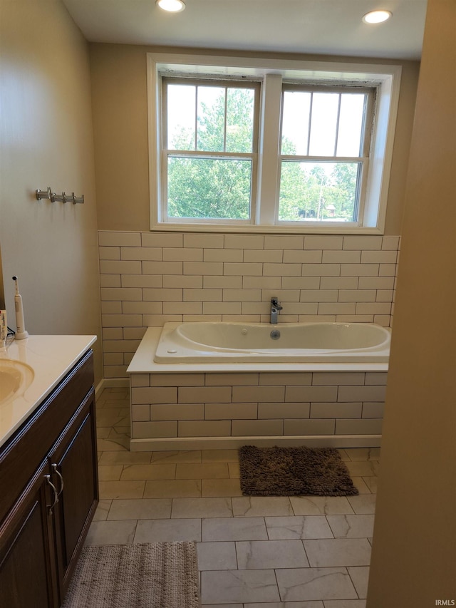 bathroom with a healthy amount of sunlight, a bath, and vanity