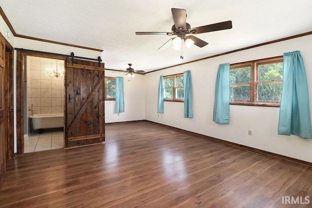 empty room featuring a barn door, dark hardwood / wood-style flooring, and a wealth of natural light