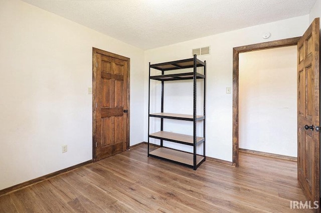 unfurnished bedroom with light hardwood / wood-style flooring and a textured ceiling