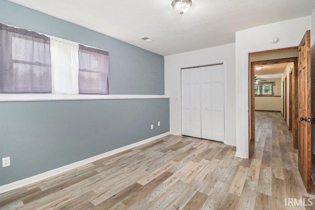 unfurnished bedroom with a closet and light wood-type flooring