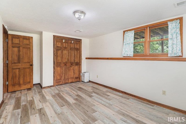 unfurnished bedroom with light hardwood / wood-style floors and a closet