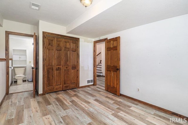 unfurnished bedroom featuring ensuite bath and light wood-type flooring