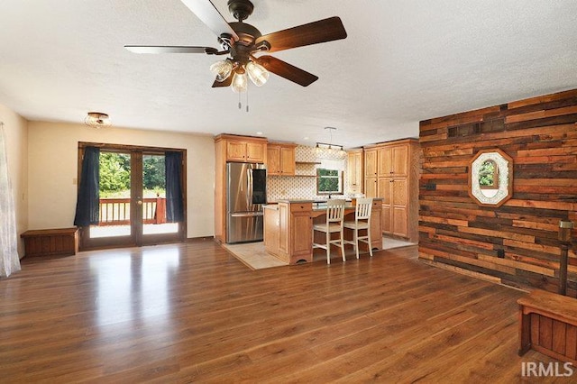 kitchen with decorative backsplash, a kitchen breakfast bar, dark hardwood / wood-style floors, and stainless steel refrigerator