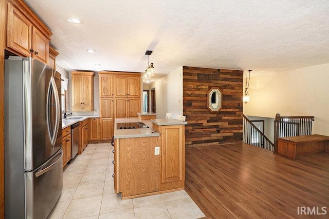 kitchen featuring hanging light fixtures, light hardwood / wood-style flooring, wooden walls, a kitchen island, and appliances with stainless steel finishes