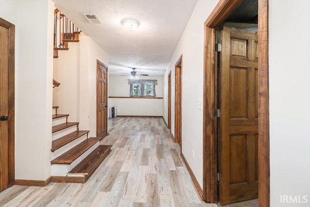 hallway featuring a textured ceiling and light wood-type flooring